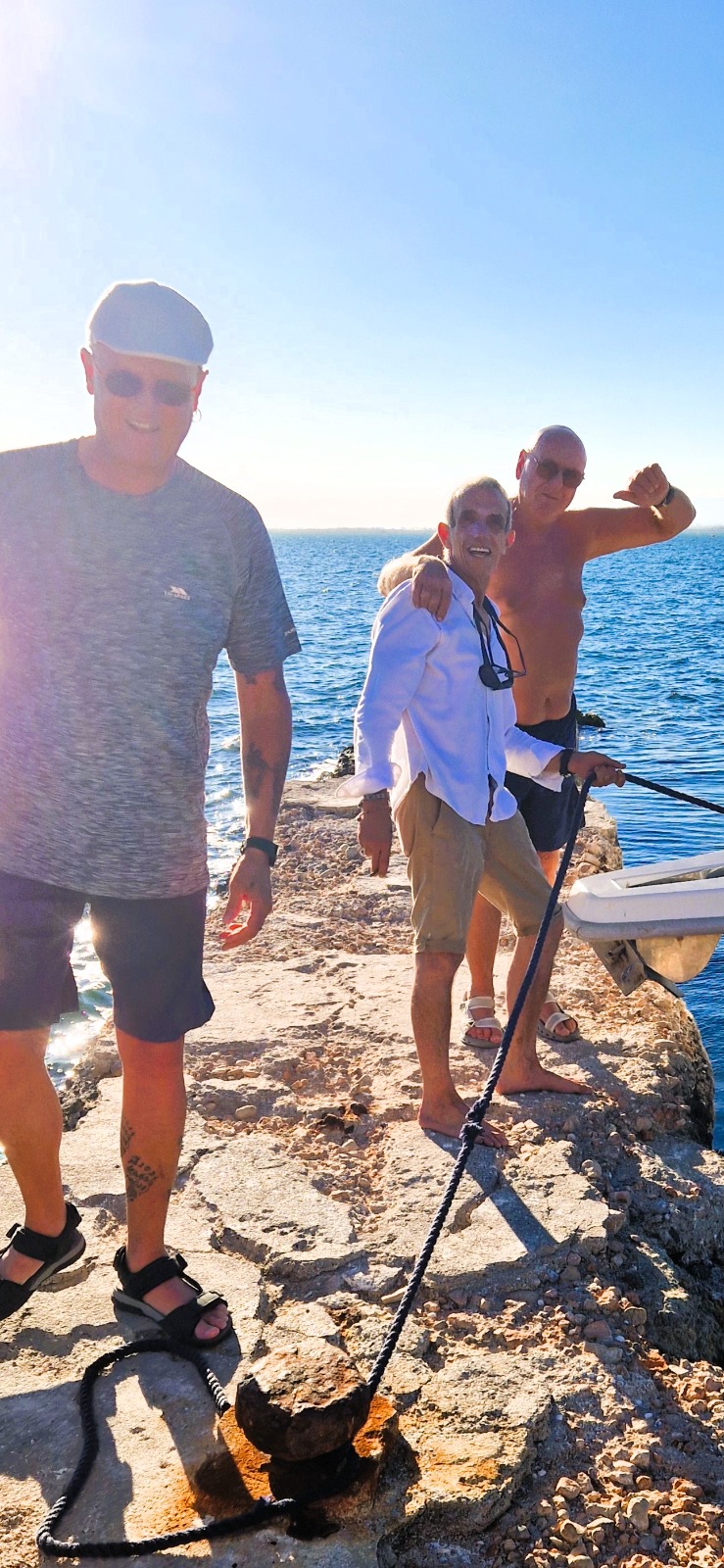 Tres participantes belgas sonriendo en el espigón de la isla